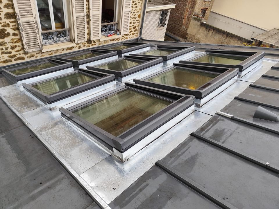 Une rangée de fenêtres de toit posées sur un toit en zinc